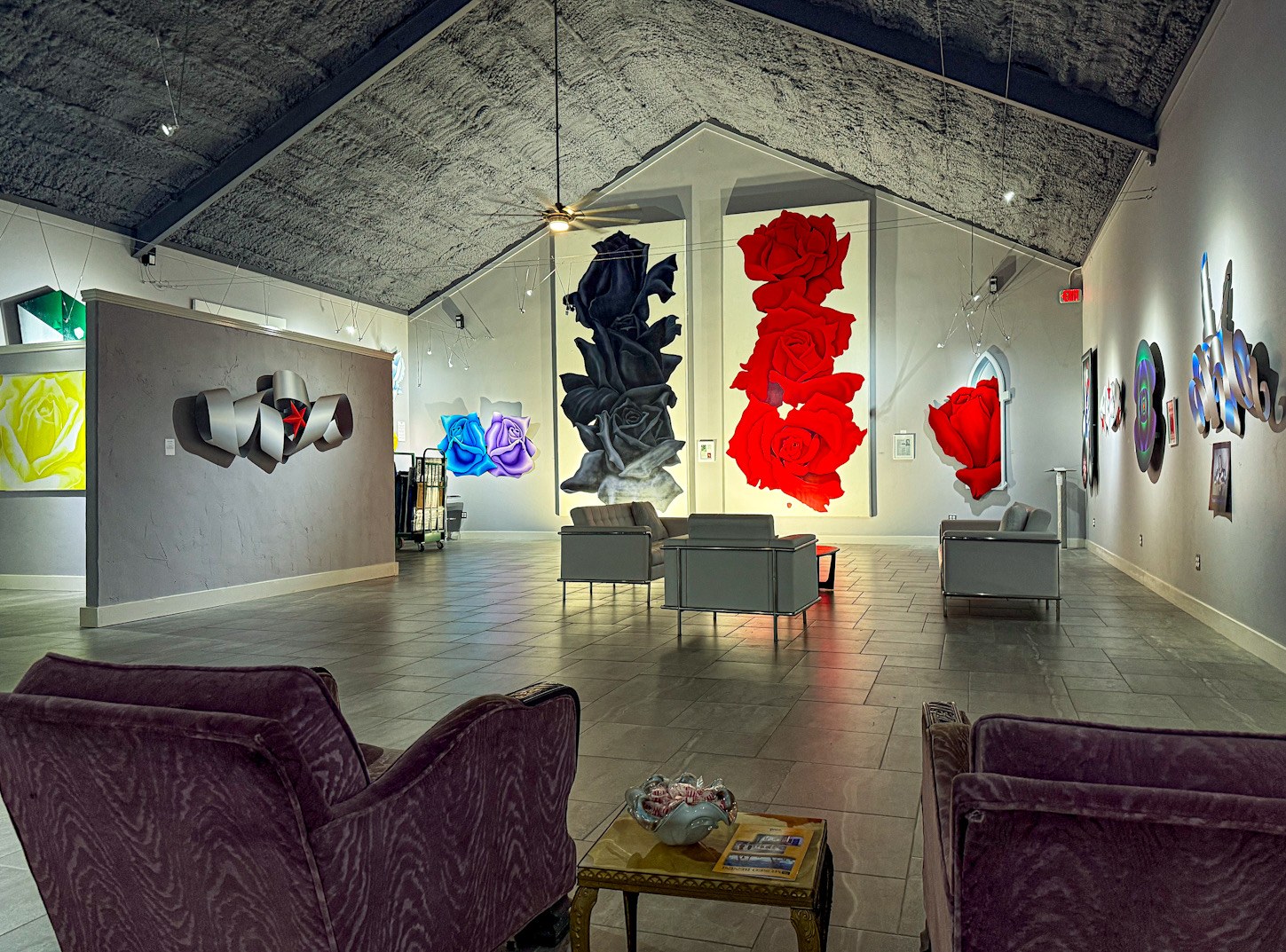 Large red rose paintings and geometric works fill a bright gallery at Museo Benini