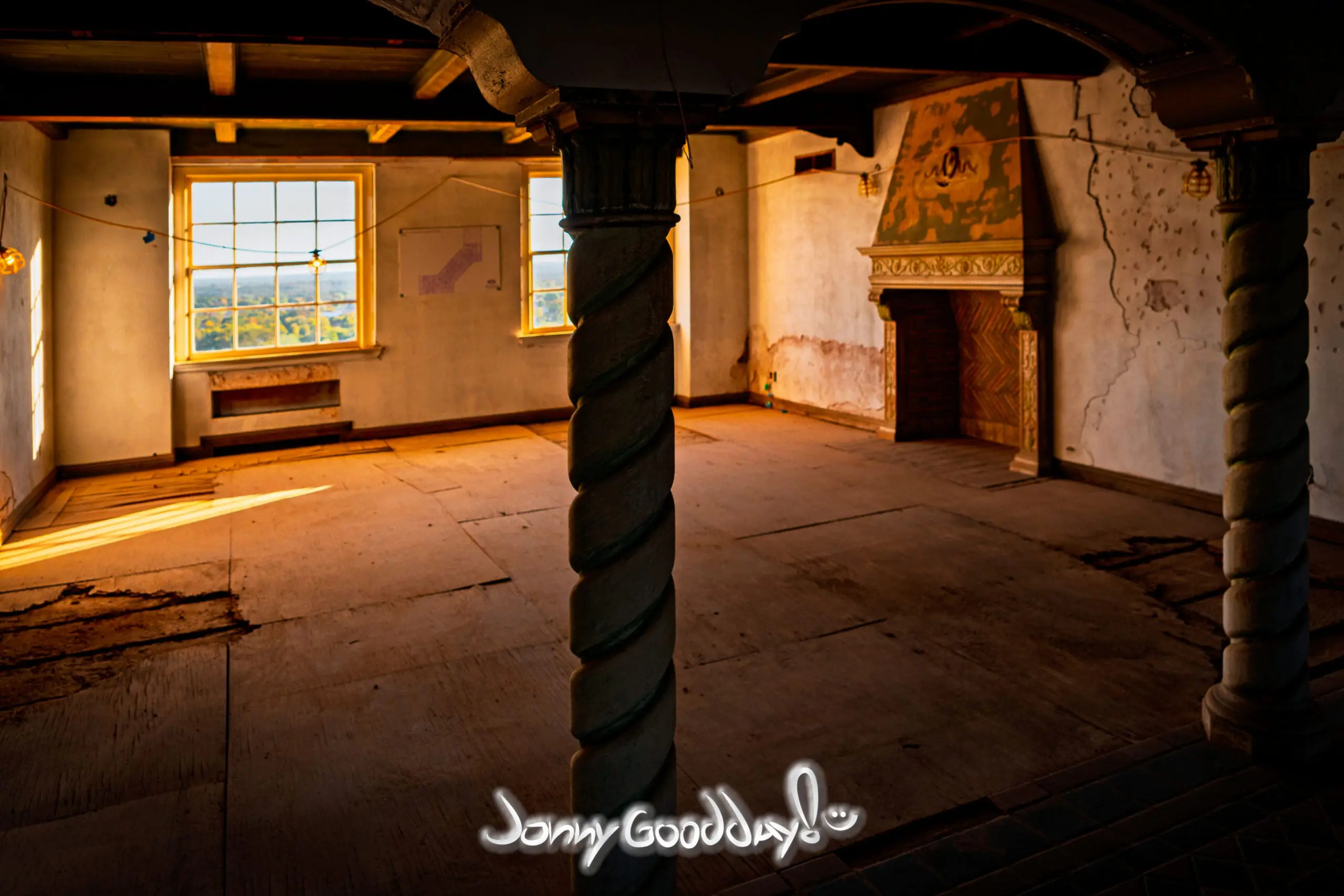 Golden light crossing an unrestored Baker Hotel room with decorative columns and a fireplace