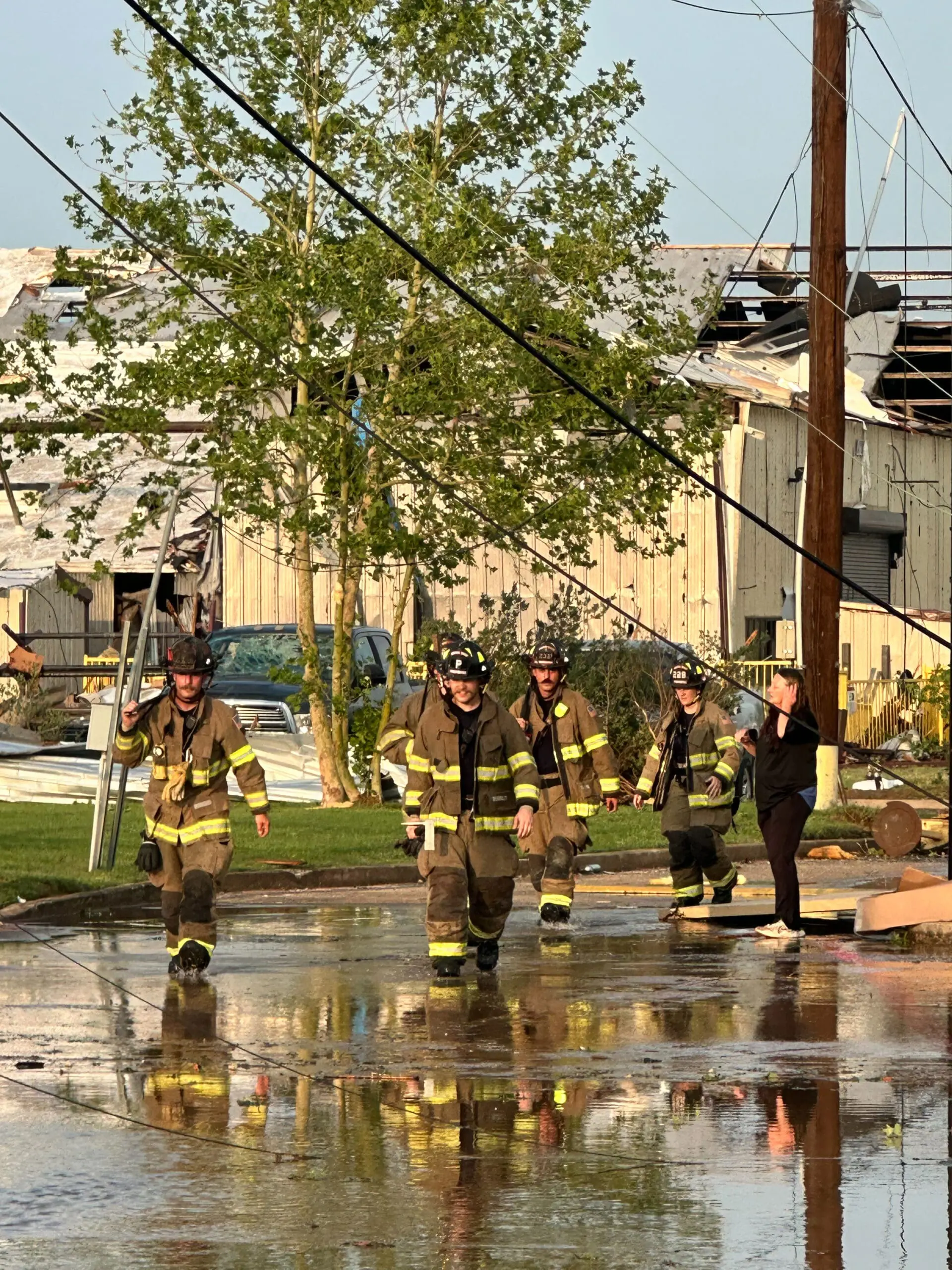 Mineral Wells firefighters walk through a flooded street after the April 2026 tornado