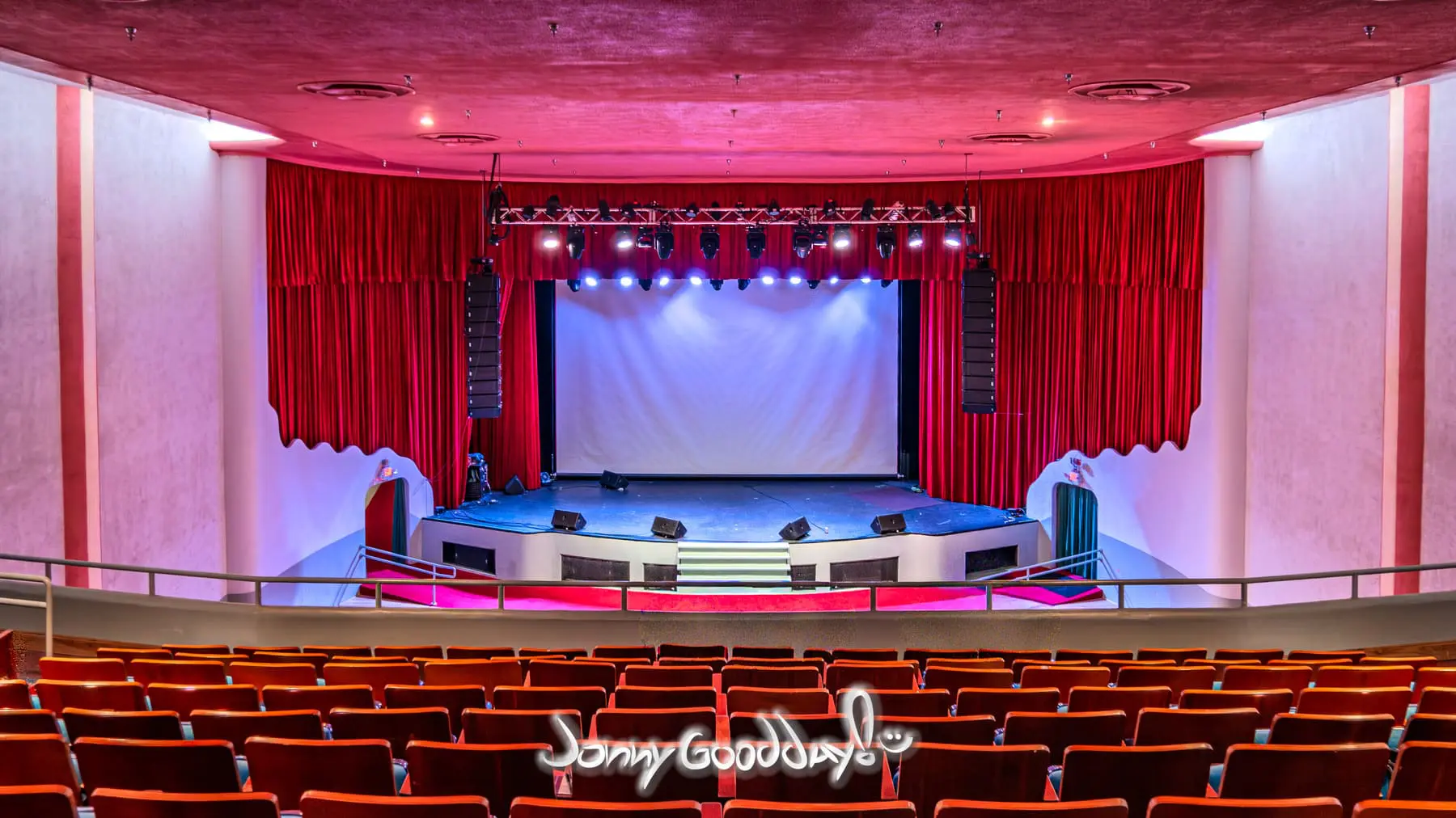 The restored Ridglea Theater auditorium with rows of seats facing the stage and red curtains in Fort Worth, Texas.