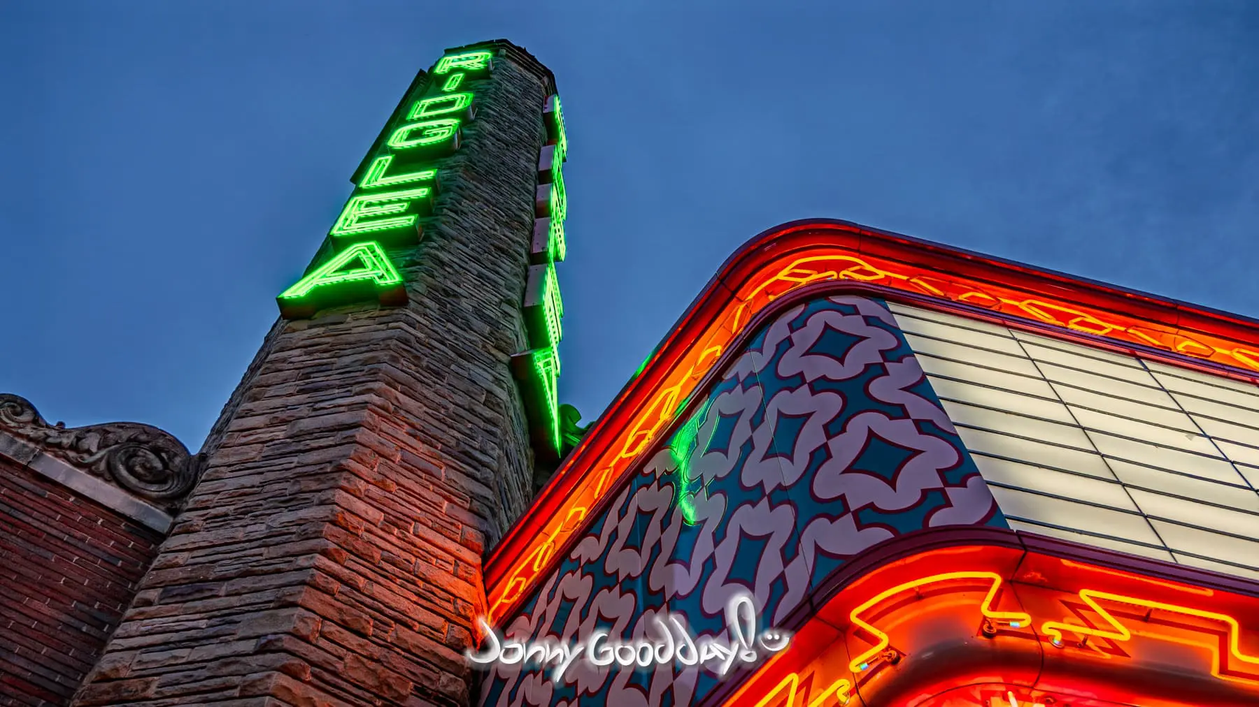 A low-angle view of the Ridglea Theater neon tower and marquee glowing after dark in Fort Worth, Texas.