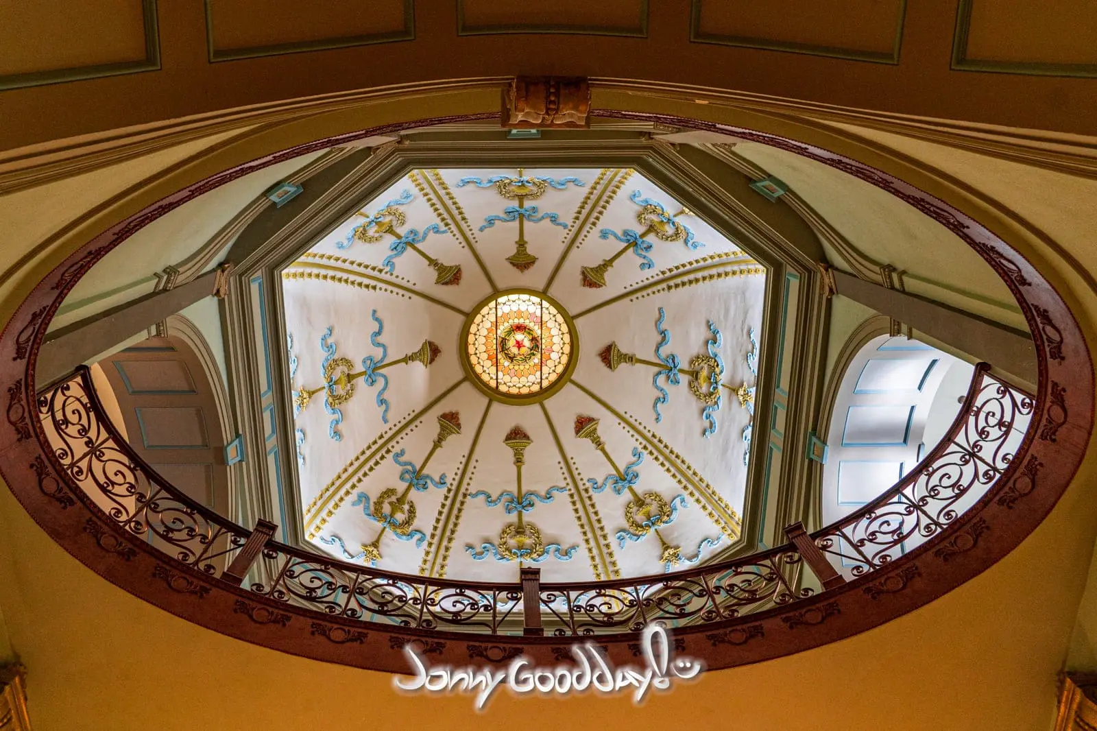 Looking up through ornate iron railings toward the stained-glass dome inside the Tarrant County Courthouse